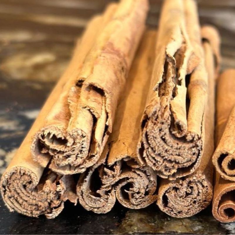 Close-up of several cinnamon sticks stacked on a dark surface.
