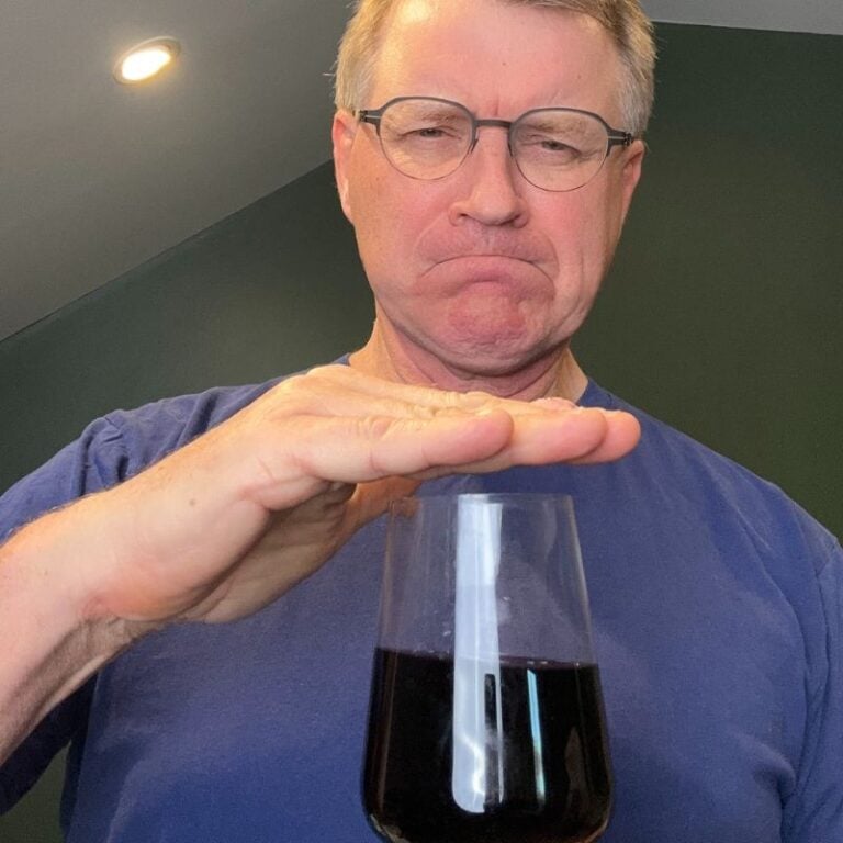 eric bakker standing with his hand over the top of a glass of red wine because alcohol and candida overgrowth are connected