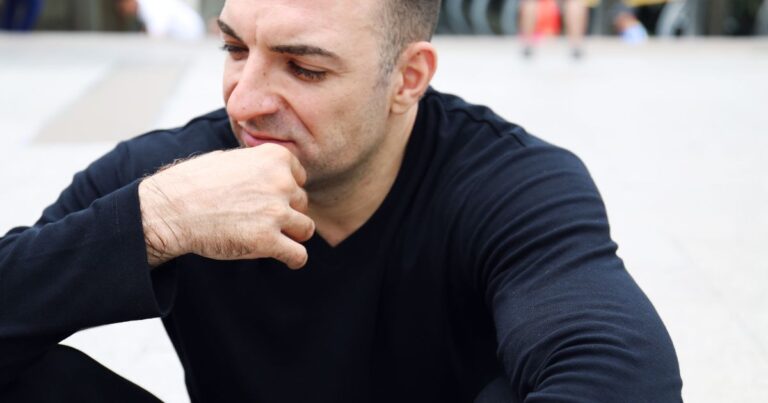 male with eyes cast downwards with a troubled expression