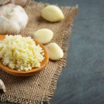 a bowl of minced garlic and cloves on table as an example of natural remedies for yeast infections