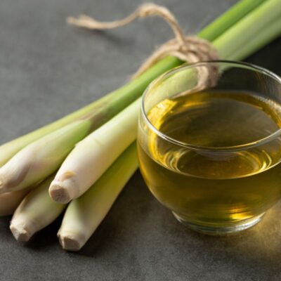 a small bundle of lemon grass and a glass of lemon grass and honey tea rest on a counter as an example of natural remedies for yeast infections