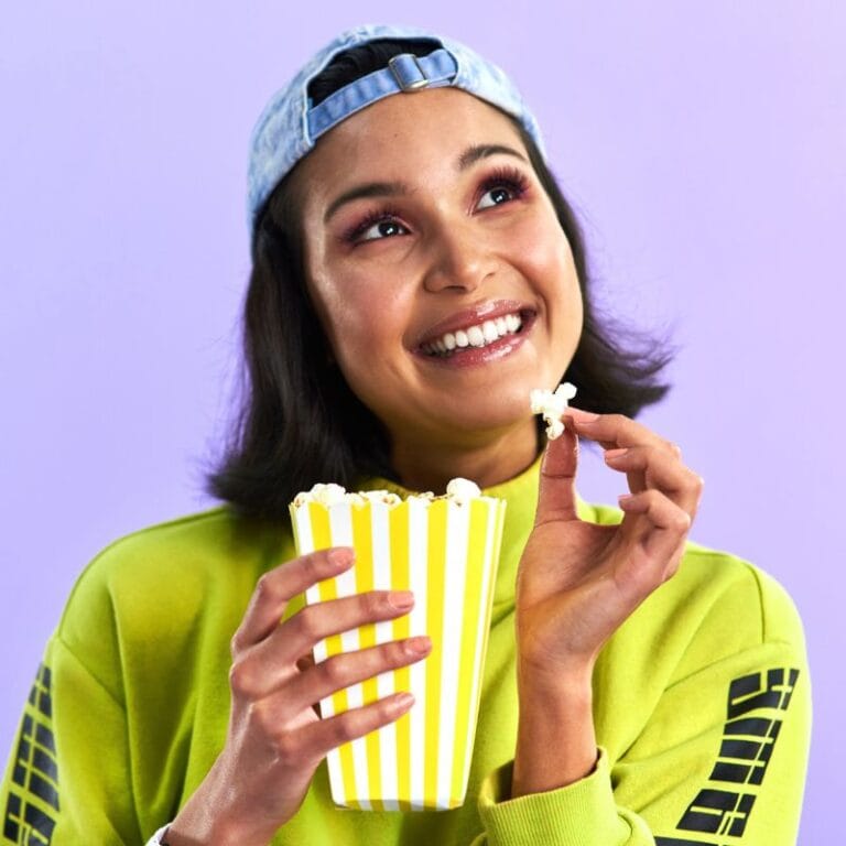 a young woman eating popcorn with a curious expression on her face asking likely can i eat popcorn on the candida diet