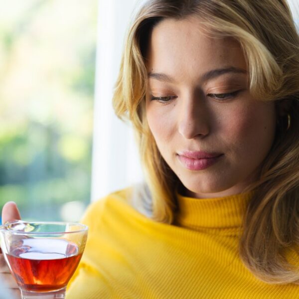 Person holding a cup of herbal tea, about to take a sip, with a calm morning atmosphere.
