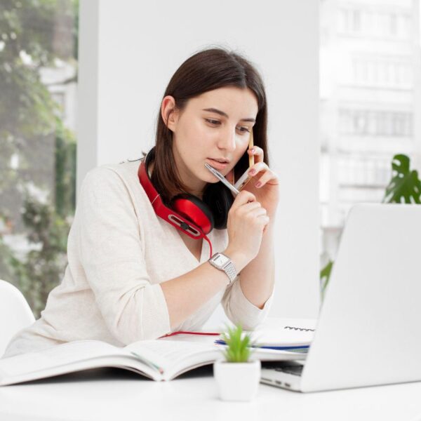 Young woman sitting at a desk with a laptop, pausing to think and reflect.