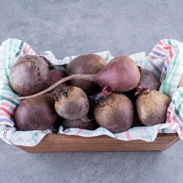 Organic beetroots on a wooden platter, natural source of betaine HCl, isolated on a grey concrete background