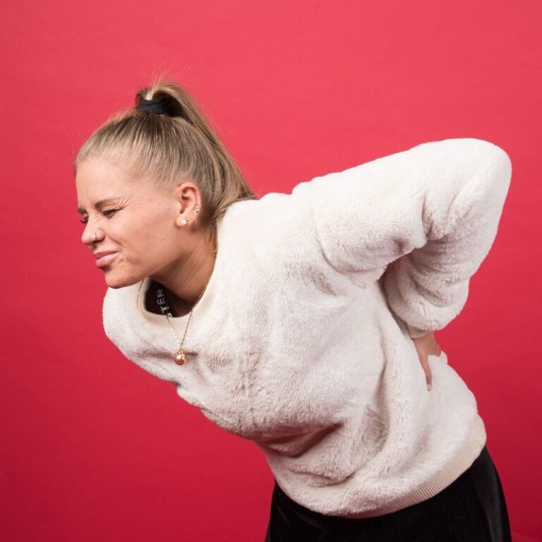 young woman bending over in pain wondering if it is candida die-off or something else