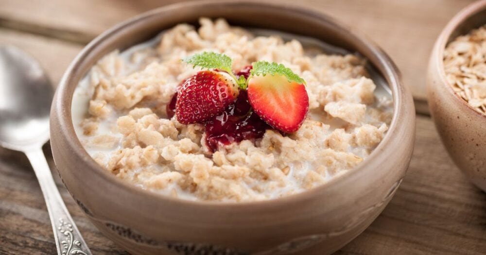 a wooden bowl of oatmeal and strawberry's on top to answer the question can i eat oats on the candida diet
