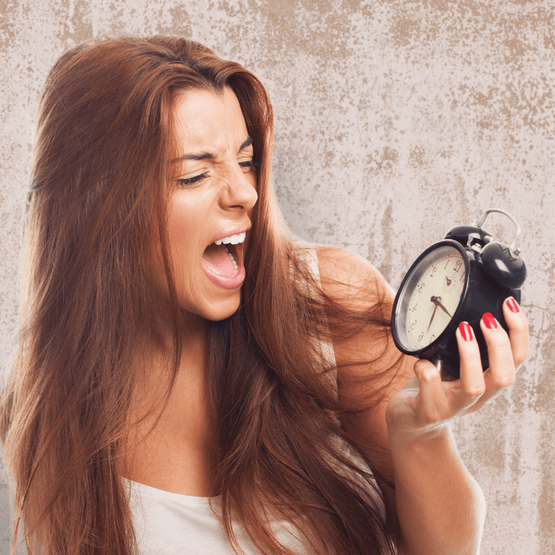 woman with long hair looking at an alarm clock and expression on face like she wants to get rid of a yeast infection in 24 hours