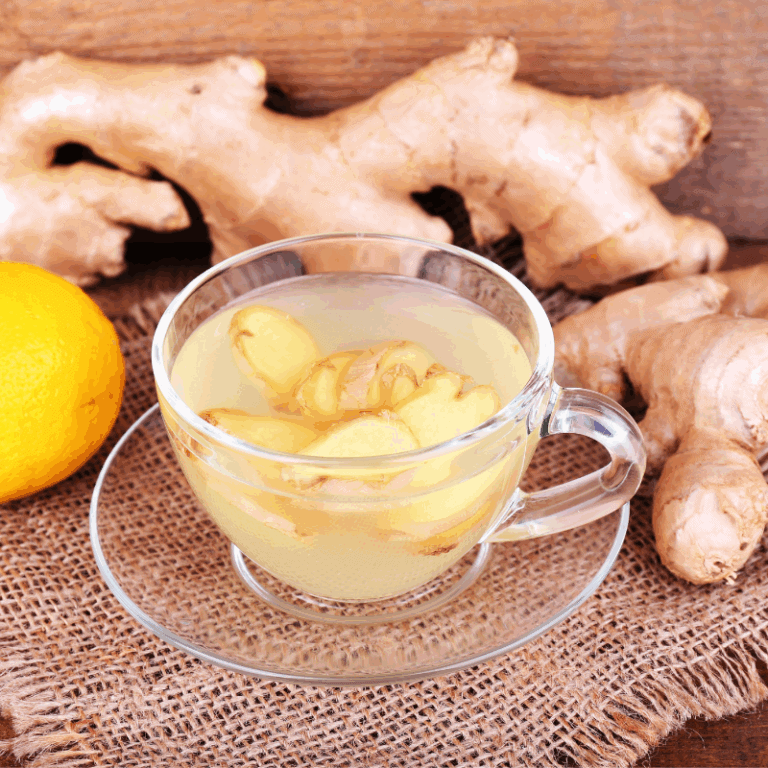 a glass cup of ginger tea with ginger root and lemon beside it on a table is great for IBS