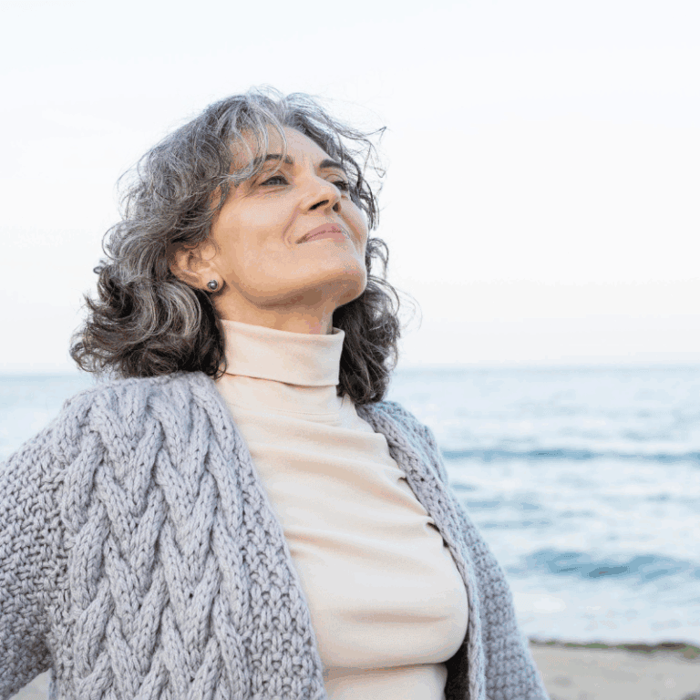 senior woman at the beach looking up with a mindful expression appreciating the world which is so important for those with alzheimer's disease
