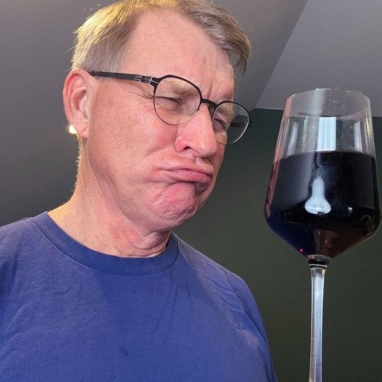 Eric Bakker frowning and holding a glass of red wine being an obvious no for the question can you drink alcohol with candida?